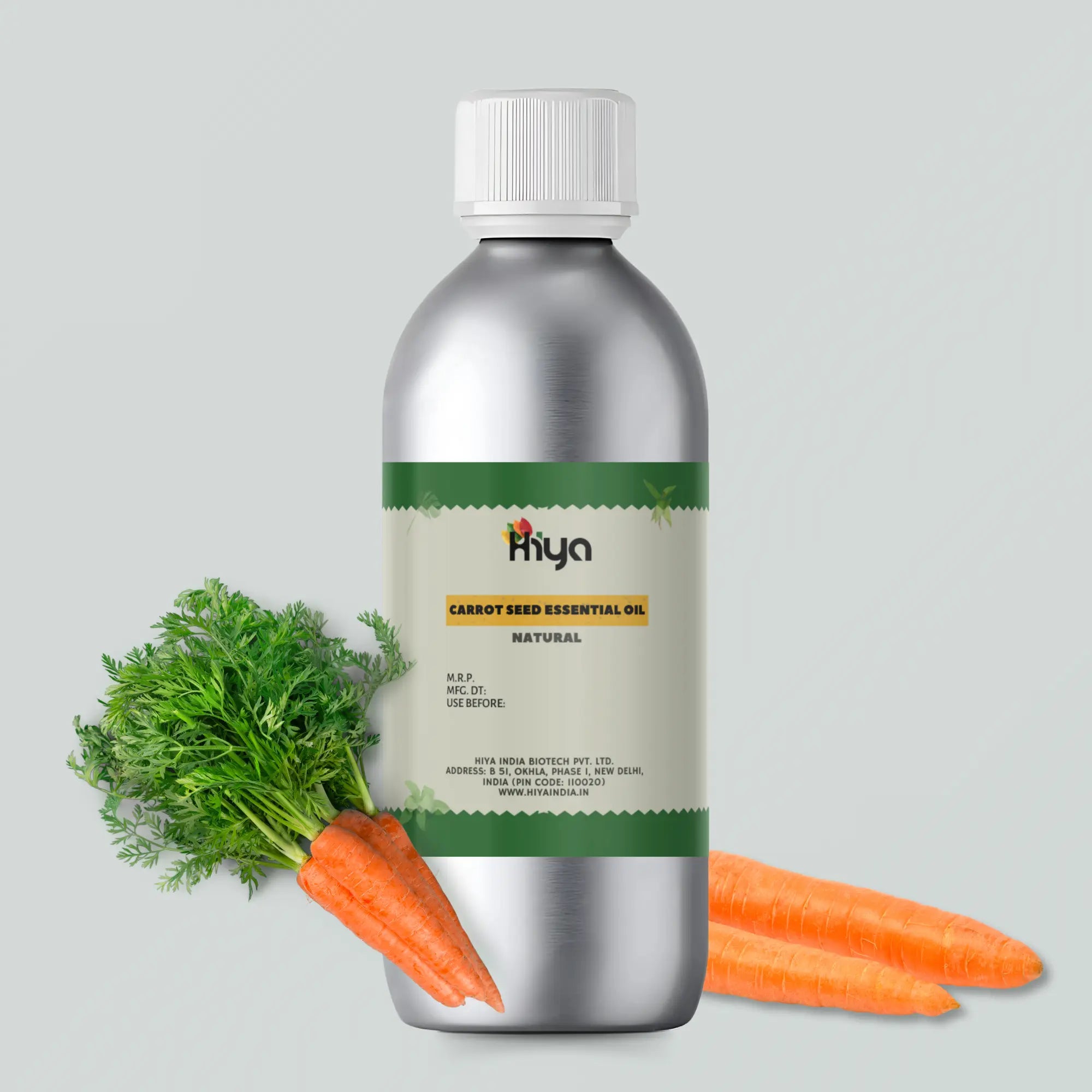 A silver bottle labeled "Hiya Natural Carrot Seed Essential Oil" is displayed alongside fresh carrots and their green tops. The label features information like M.R.P., manufacturing date, expiration date, and company address, including Hiya India Biotech Pvt. Ltd. in New Delhi, India. The website "www.hiyaindia.in" is also mentioned.