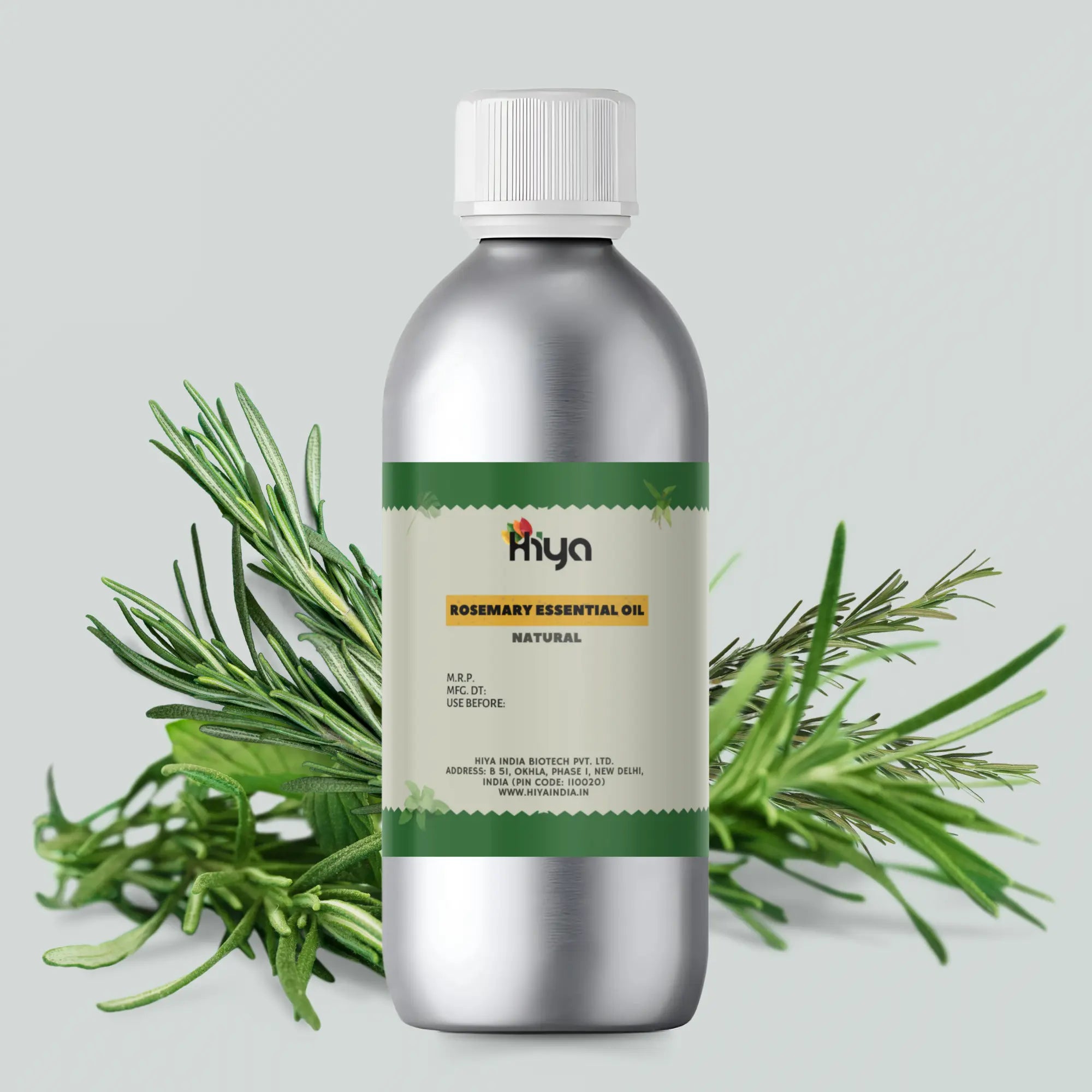 A metallic bottle with a white cap labeled "Hiya Rosemary Essential Oil Natural" is displayed surrounded by sprigs of fresh rosemary. The label highlights product details such as M.R.P., manufacturing date, expiration date, and the company's information: Hiya India Biotech Pvt. Ltd., based in New Delhi, India, along with the website "www.hiyaindia.in.