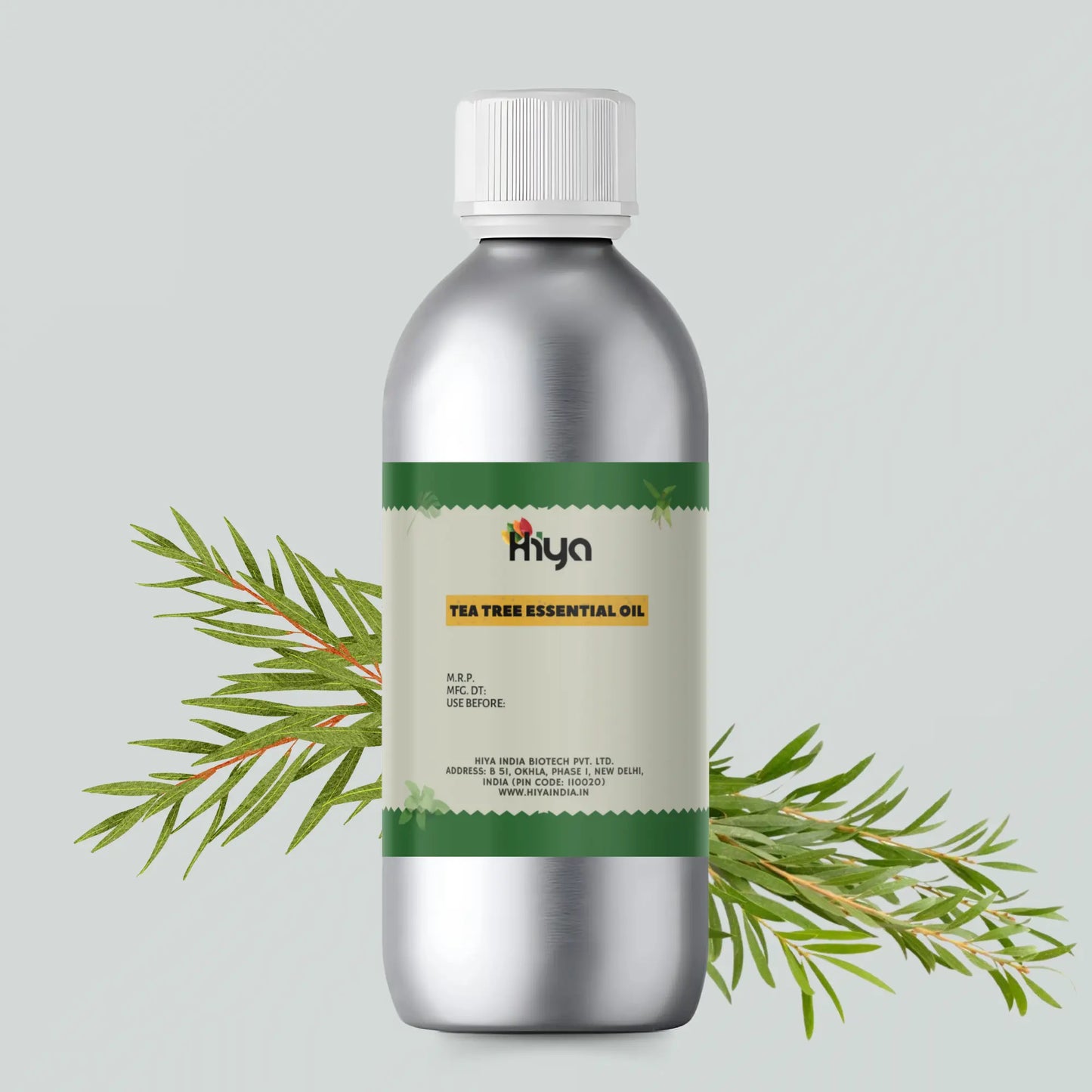 Hiya Tea Tree Essential Oil bottle with a metallic finish and white cap, featuring a green label. The label reads "Tea Tree Essential Oil" by Hiya India Biotech Pvt. Ltd., New Delhi, India. Sprigs of fresh tea tree leaves surround the bottle, emphasizing its natural ingredients and benefits for aromatherapy and skin care.